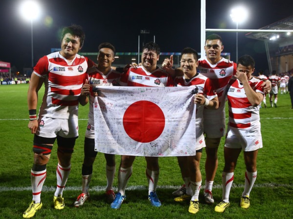 Japanese players with a signed Japanese flag, bow out of Rugby World Cup, with their heads held high.